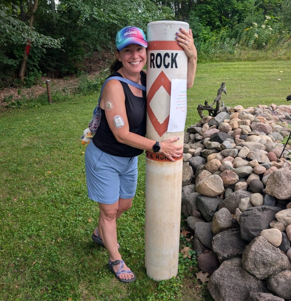 Woman beside a white hazard marker post on the rocks