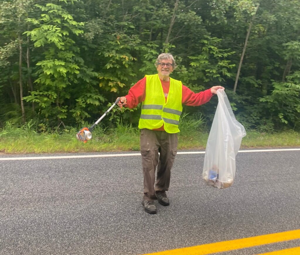 Volunteer in a safety vest picking up litter along the highway