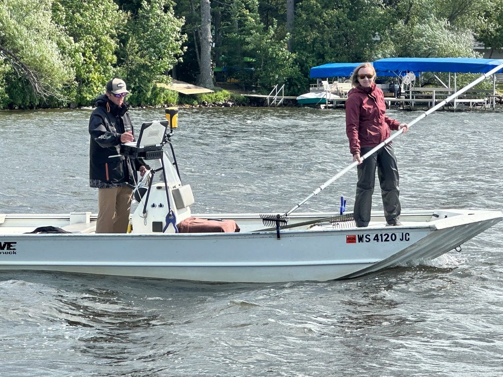 People aboard a boat, possibly holding a pole or marker