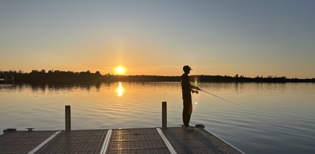 Person fishing from a dock at sunset