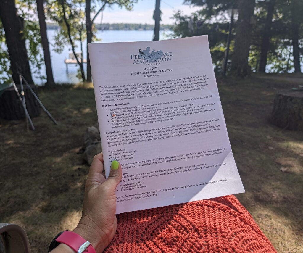 Printed newsletter held up in front of the lake.